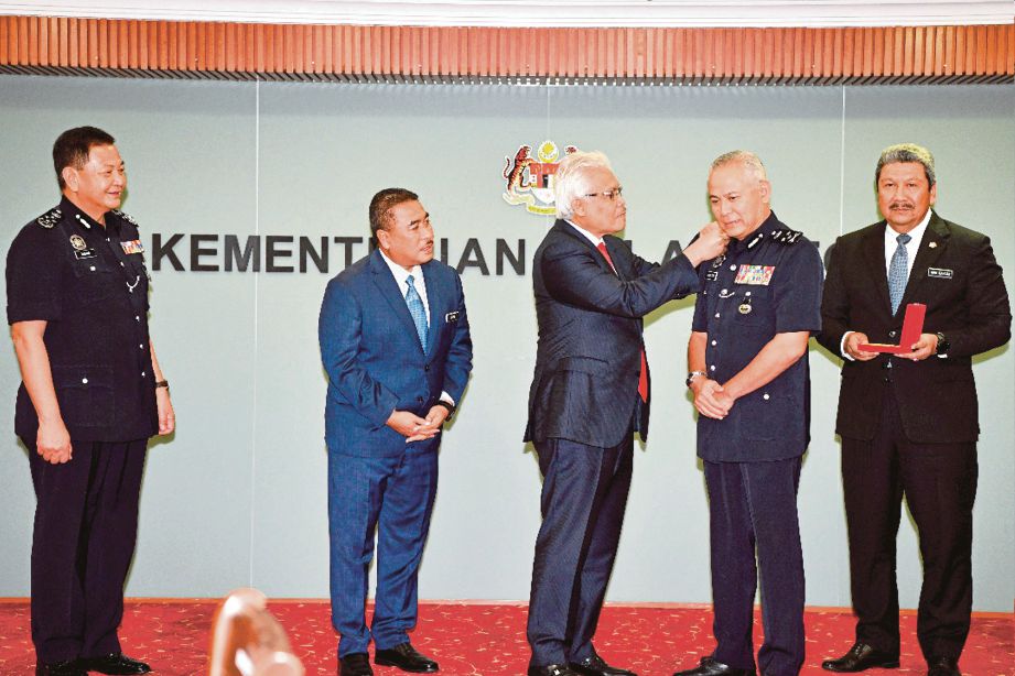 DATUK Seri Hamzah Zainudin menyempurnakan pemakaian pangkat pada Datuk Seri Acryl Sani  Abdullah Sani (dua dari kanan). FOTO ihsan KDN