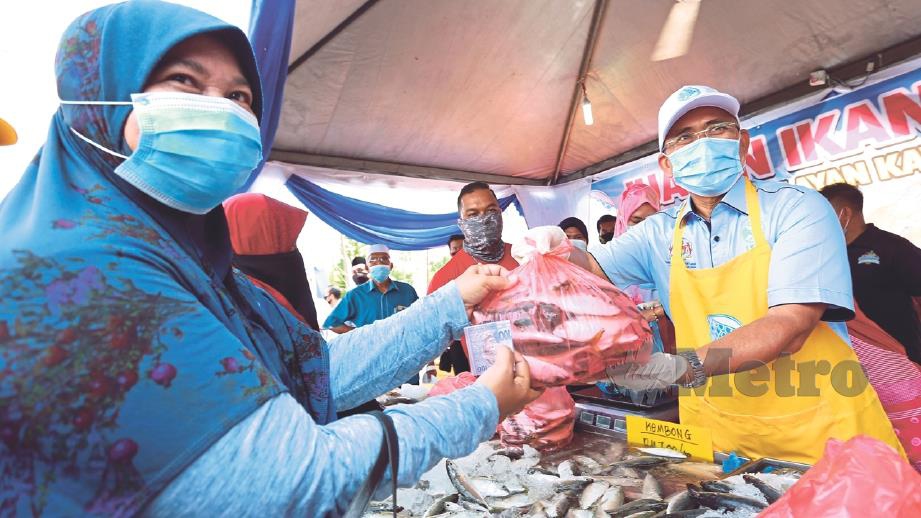 RONALD (kanan) menyerahkan ikan kembung  dijual secara lelong oleh LKIM kepada pengunjung di Mini Karnival Industri Makanan Bukit Gantang 2020 di Dewan Bunga Raya, Changkat Jering, semalam. 