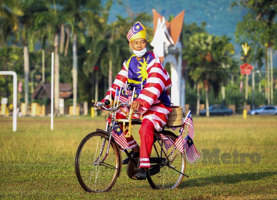 MUSA mengayuh basikal klasik dengan mengenakan pakaian menggunakan Jalur Gemilang ketika menyertai Seri Menanti Funride  Merdeka@Komuniti di padang awam Seri Menanti. FOTO Azrul Edham Mohd Aminuddin