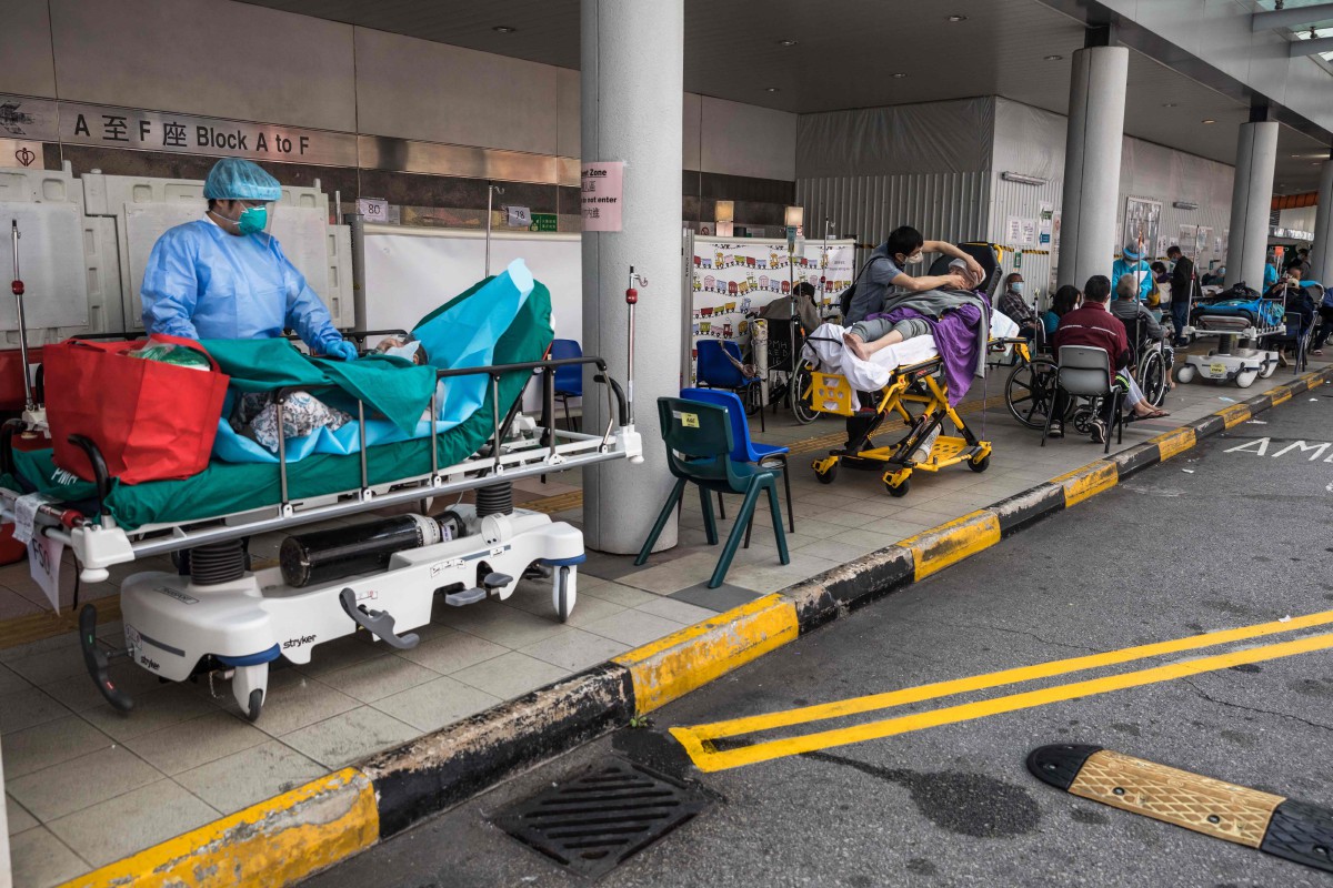 Kakitangan kesihatan memeriksa pesakit yang ditempatkan sementara di luar bahagian kecemasan hospital di Hong Kong. - FOTO AFP