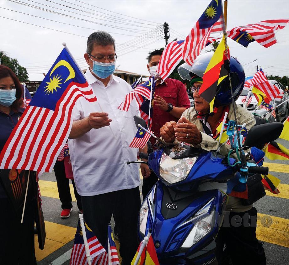 DATUK Saifuddin Abdullah menyapa Joni Bol yang mengunggang motosikal yang dihiasi dengan Jalur Gemilang dan bendera Sarawak di Sibu, hari ini. FOTO Mohd Roji Kawi