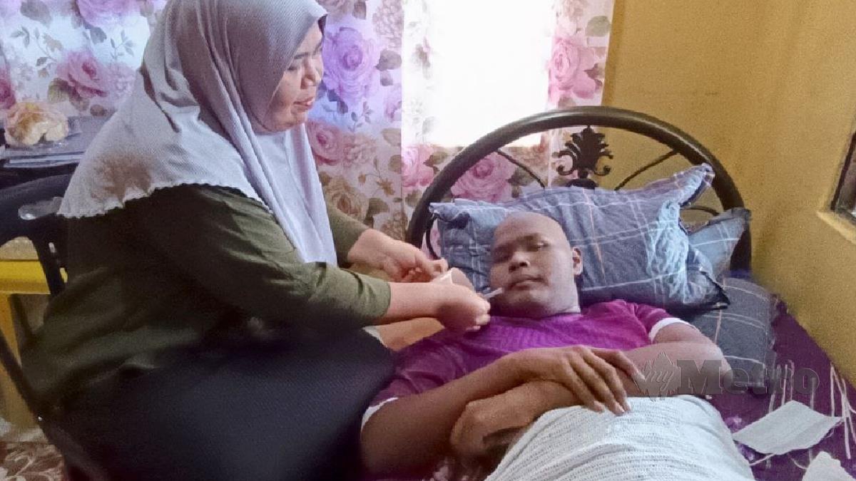 Fauziah Ahmad menyuap minuman untuk anaknya, Muhammad Firdaus Mohd Zul, 15, yang menghidap kanser tulang sejak Mei lalu menyebabkan dia terlantar dan tidak dapat bergerak.STR/ZULIATY ZULKIFFLI