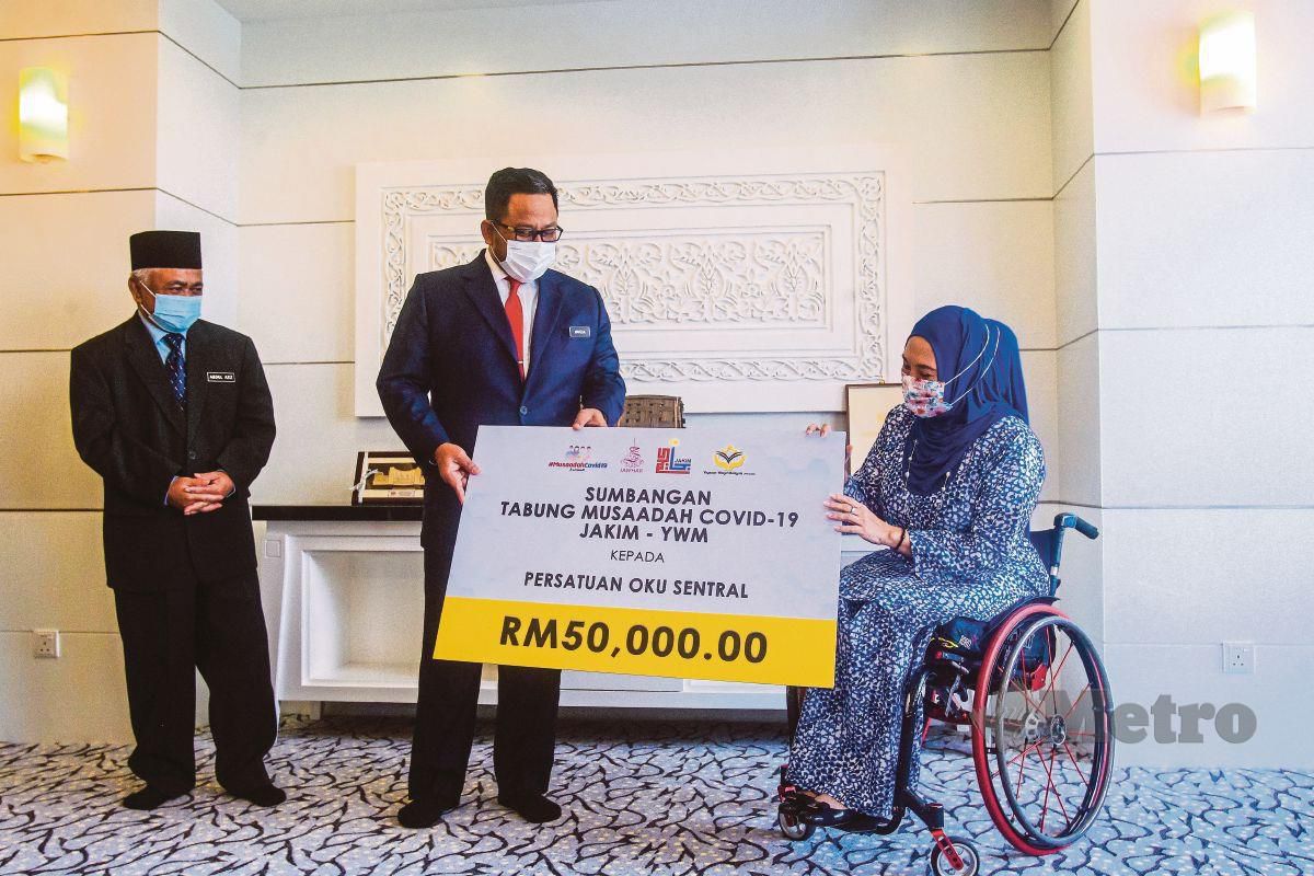 AHMAD Marzuk Shaary (tengah) menyampaikan sumbangan RM50,000 daripada Tabung Musaadah COVID-19 JAKIM-Yayasan Wakaf Malaysia (YWM) kepada Senator Ras Adiba Mohd Radzi (kanan) di Kompleks Islam Putrajaya. FOTO Luqman Hakim Zubir