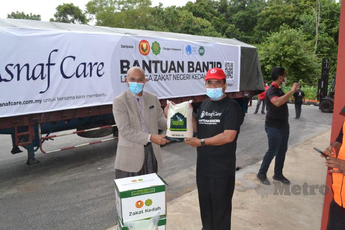 DATUK Seri Dr Sallehuddin Ishak (kiri) mewakili Kerajaan Pahang menerima sumbangan beras daripada  Syeikh Zakaria Othman di Kuantan. FOTO Asrol Awang