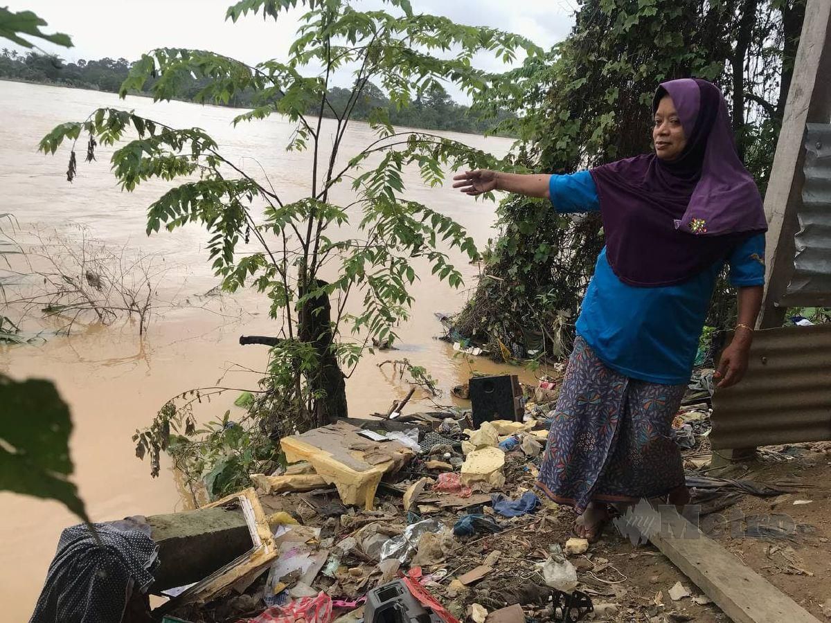 ROSMAH Deraman menunjukkan hakisan tanah yang berlaku di bahagian belakang rumahnya di Kampung Surau Kota. FOTO Hazira Ahmad Zaidi