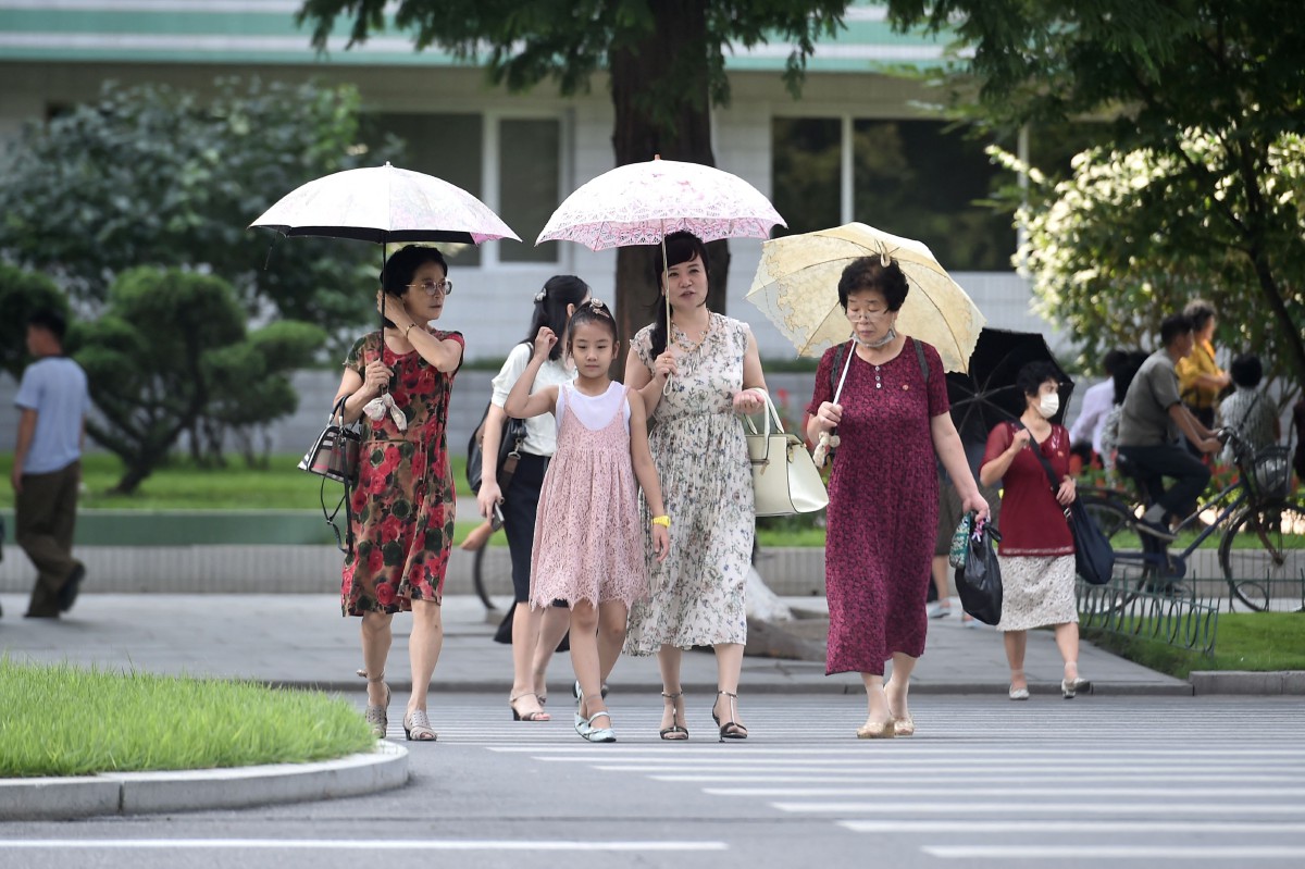 Penduduk Korea Utara berjalan di Ryomyong, Pyongyang selepas mandat pemakaian pelitup muka ditarik balik. - FOTO AFP