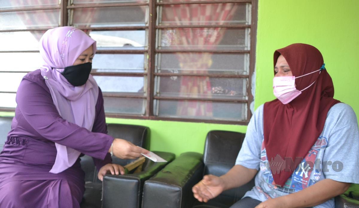 ROSDIANA (kanan) menerima sumbangan daripada Norihan sambil di Kampung Telok Gong, Masjid Tanah. FOTO Hassan Omar