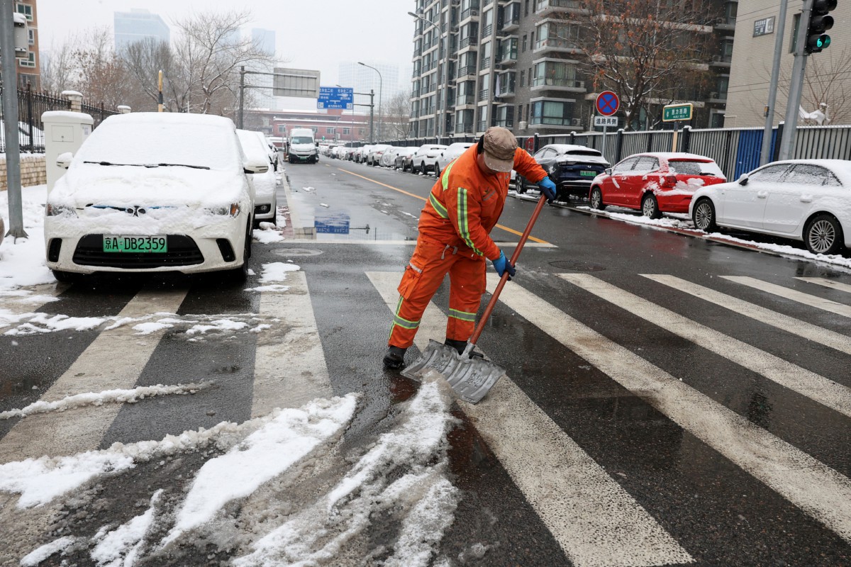 Pekerja membersihkan salji di jalan raya. - FOTO Reuters