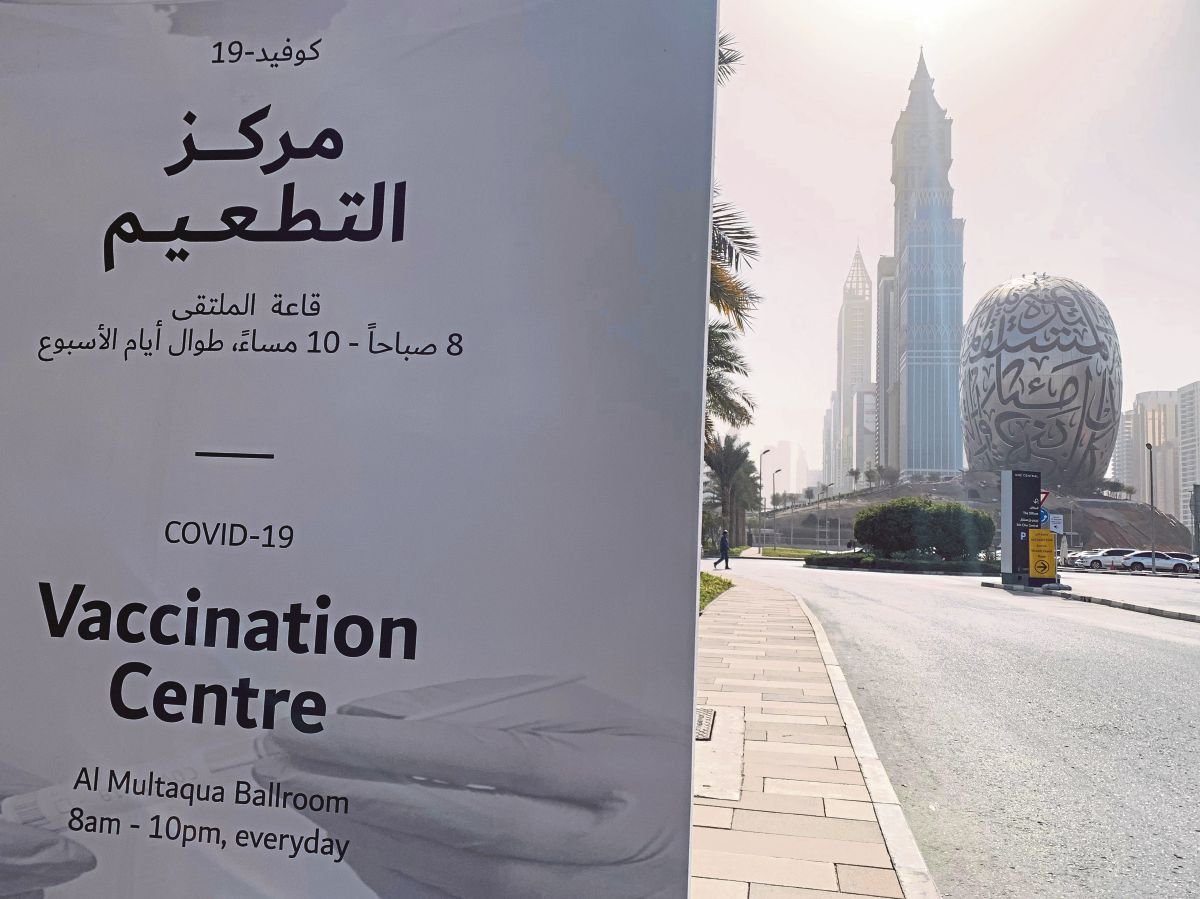 POSTER iklan memberitahu orang ramai mengenai lokasi pusat vaksinasi COVID-19 yang ditetapkan di daerah pusat kewangan Dubai. FOTO AFP