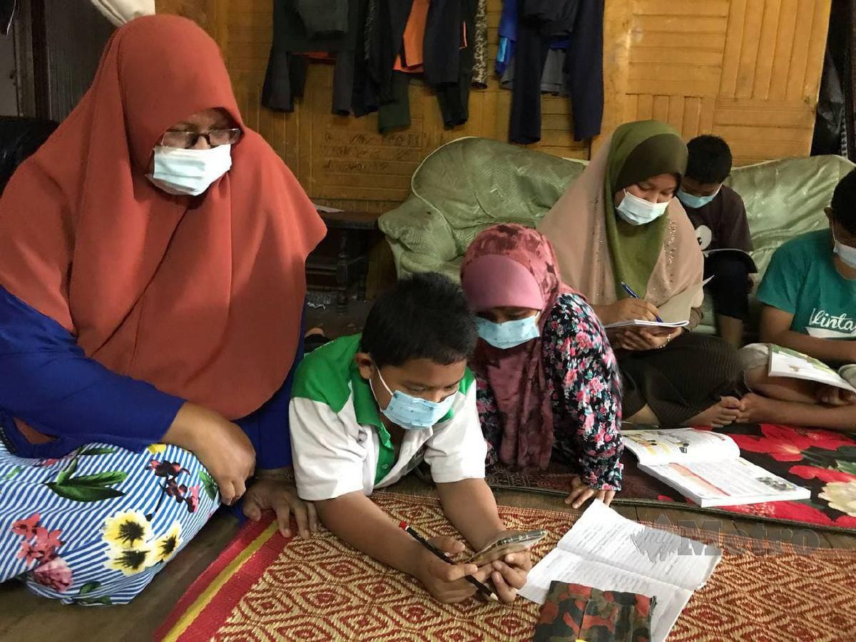 HASYANI Jusoh (kiri) memantau anak-anaknya yang mengikuti Pengajaran dan Pembelajaran di Rumah (PdPR) di rumahnya di Kampung Sri Kulim, Melor. FOTO Hazira Ahmad Zaidi