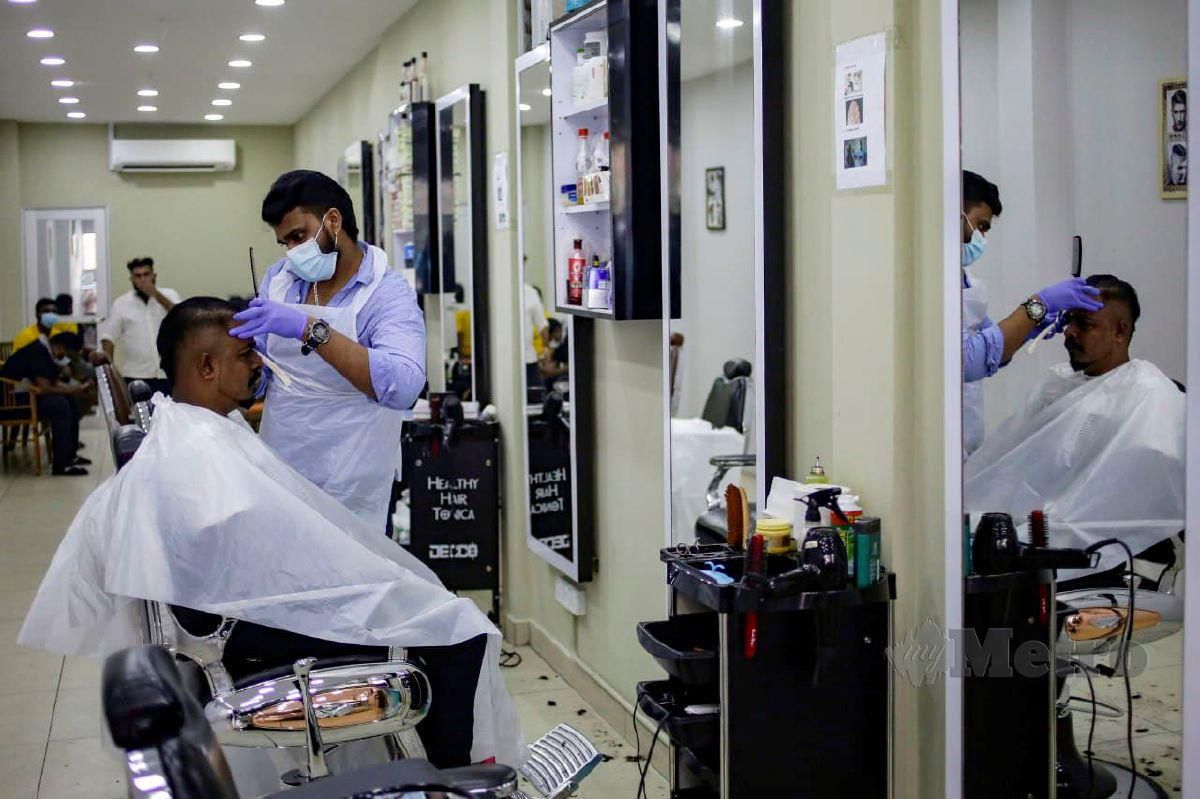 PEKERJA kedai gunting rambut menggunakan pelitup muka ketika menggunting rambut pelanggan dengan mematuhi SOP yang lebih ketat. FOTO Aizuddin Saad