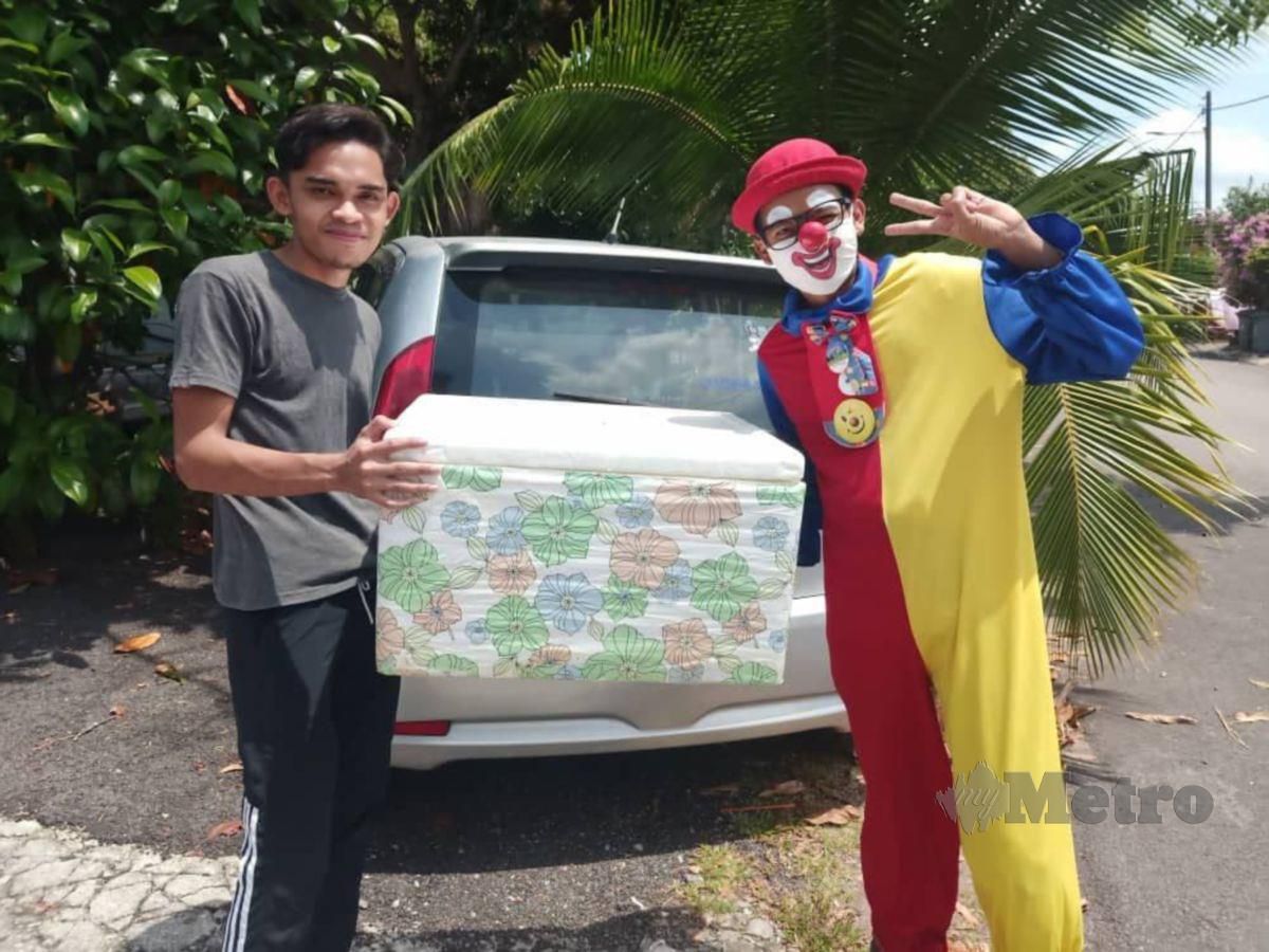 MOHD Fahmi Mohamad Nadzri atau gelaran  Speed de Clown mengenakan kostum badut ketika menghantar makanan dengan keretanya. FOTO Nazri Abu Bakar