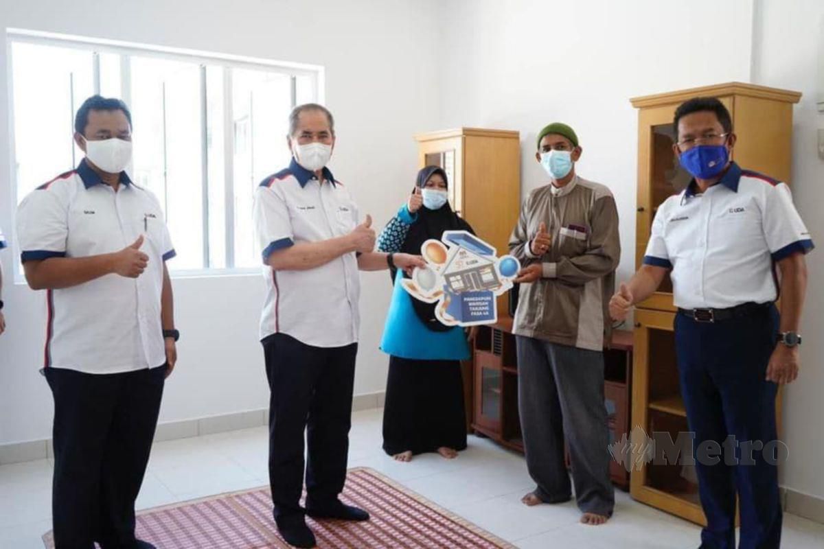 DATUK Seri Dr Wan Junaidi Tuanku Jaafar (dua dari kiri) ketika menyerahkan kunci rumah baru kepada penduduk asal Tanjung Tokong Fasa 4A. 