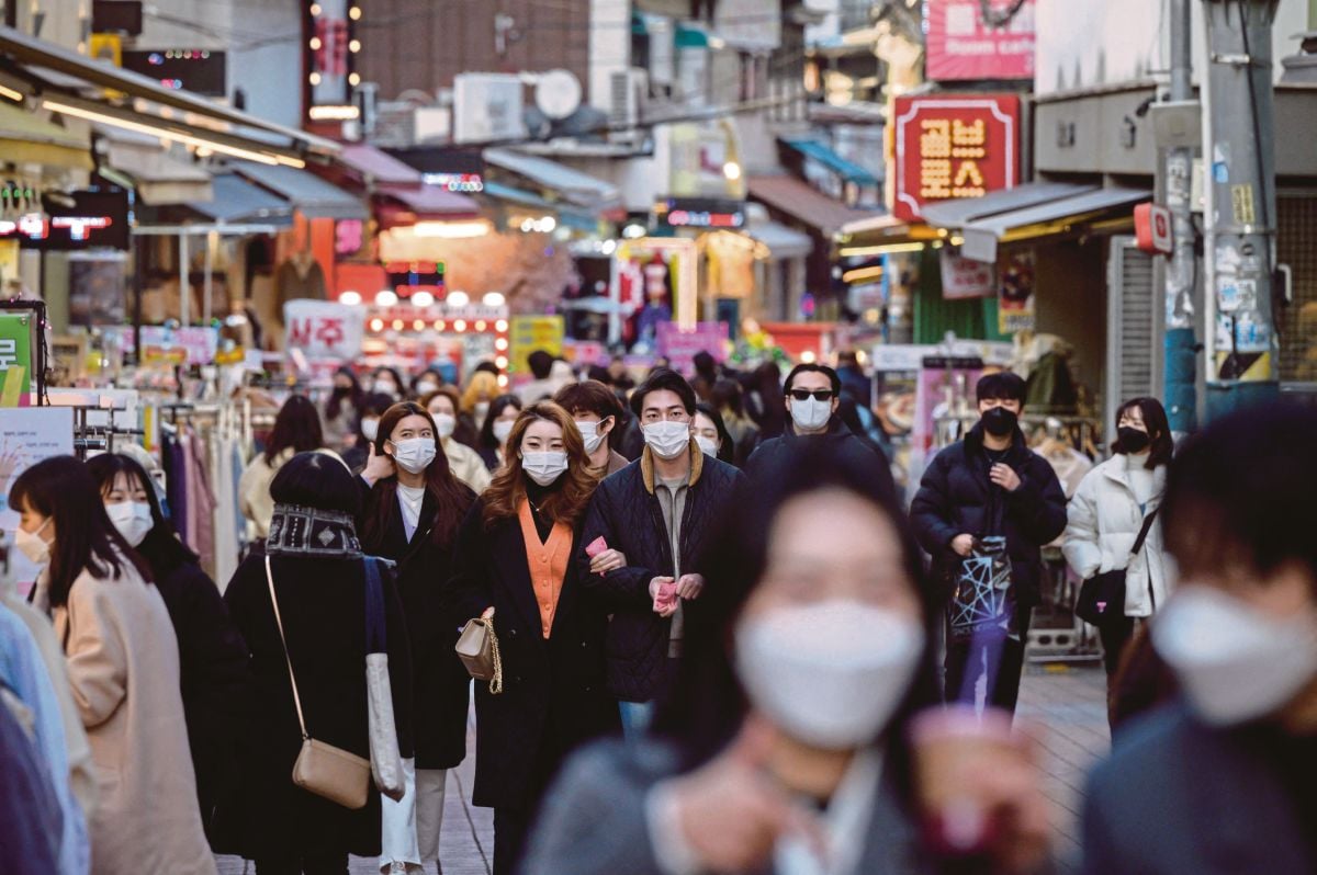 ORANG ramai berjalan di jalan komersial di Seoul. FOTO AFP