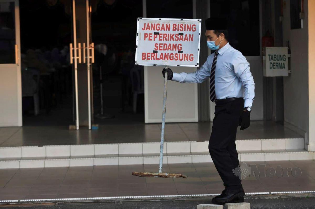 PENGAWAS peperiksaan membawa papan tanda amaran semasa calon menduduki SPM ketika tinjauan di SMKA Dato Haji Abbas. FOTO Ghazali Kori