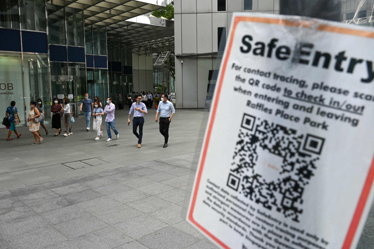 Papan tanda pengesanan kontak dipaparkan berhampiran bangunan pejabat di pusat kewangan Raffles Place, Singapura. - FOTO AFP