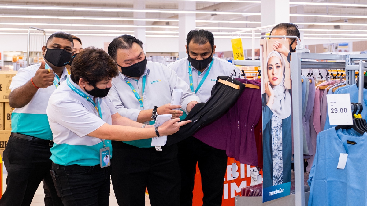PRESIDEN Lotus’s Malaysia, Kenneth Chuah (tengah) melihat pakaian yang disediakan sempena kempen Raya Mesti Raya.