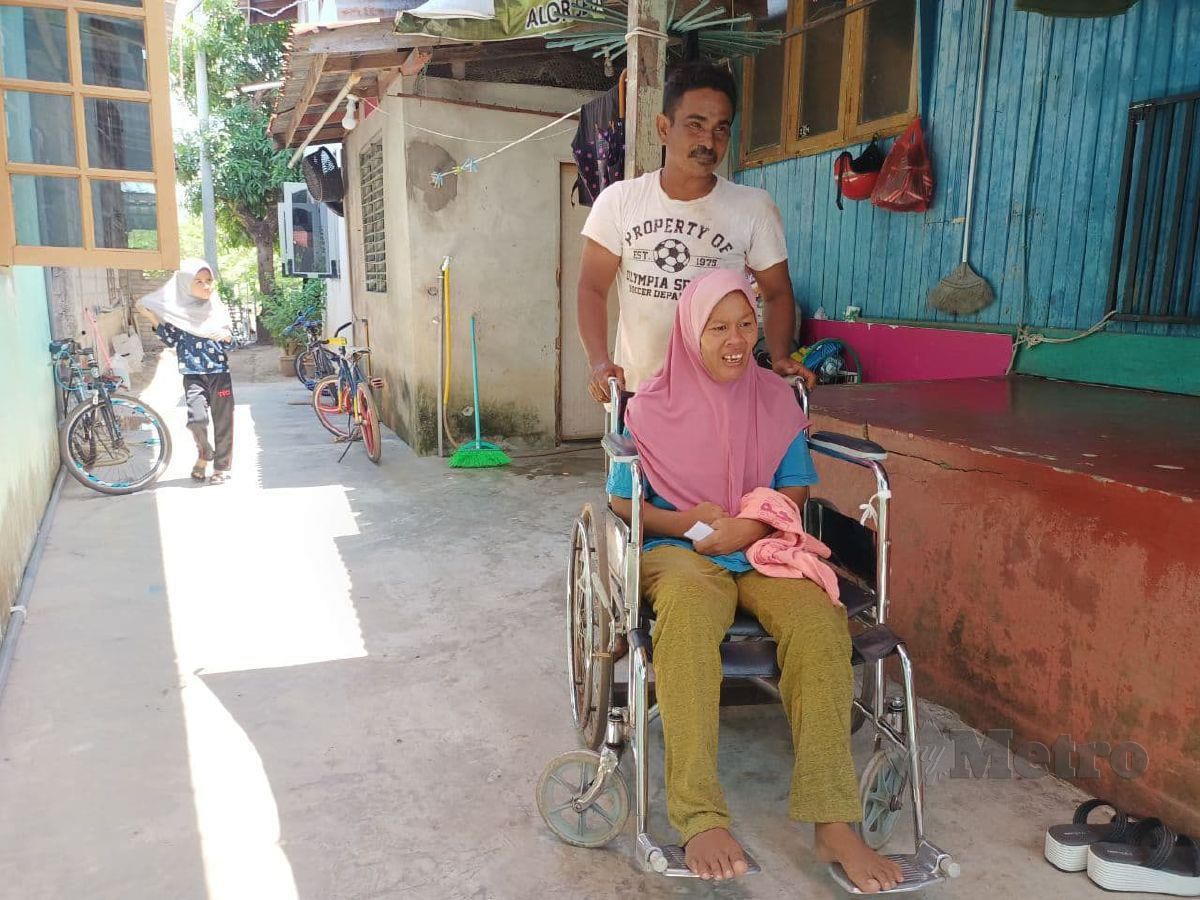 AMRAN menolak kerusi roda untuk membawa isterinya, Norliza Mahat yang diserang strok mengambil angin selepas pulang dari tempat kerja ketika ditemui di rumahnya di Kampung Tanjong Che Mas. FOTO Siti Rohana Idris