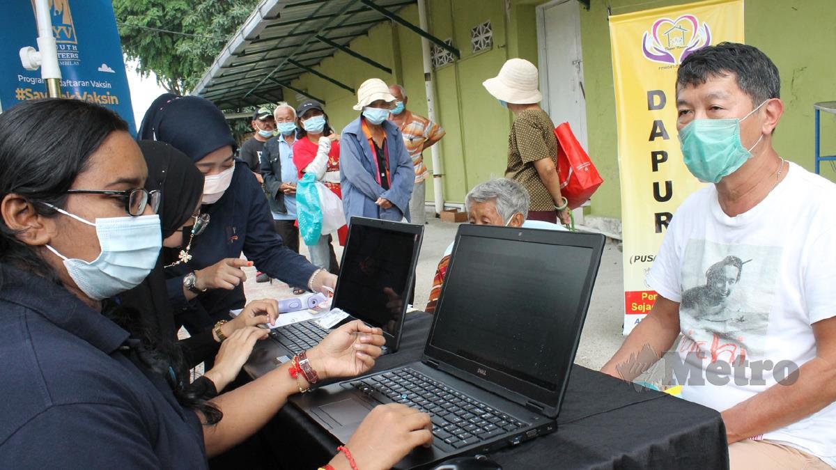 SUKARELAWAN BNYN (kiri) membuka kaunter membantu gelandangan mendaftar aplikasi MySejahtera sebagai penerima vaksin Covid-19 di perkarangan pusat Dapur Kaunsar Seremban. FOTO Mohd Amin Jalil
