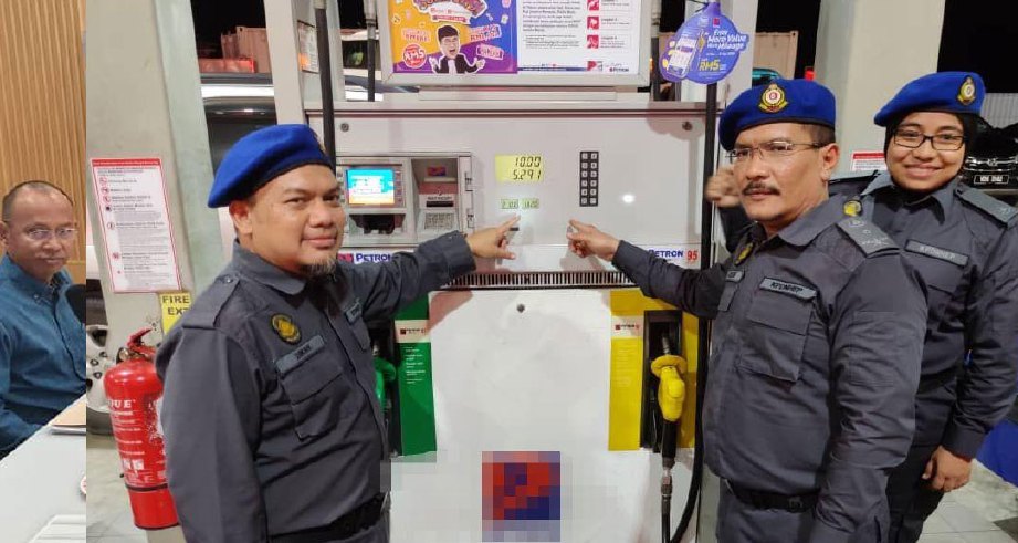 MUHAMAD Zikril  (kiri) menunjukkan harga terkini bahan api petrol pada salah satu pam minyak sempena Ops Nozel di sebuah stesen minyak di Sungai Burong, malam tadi. FOTO IHSAN KPDNHEP Selangor