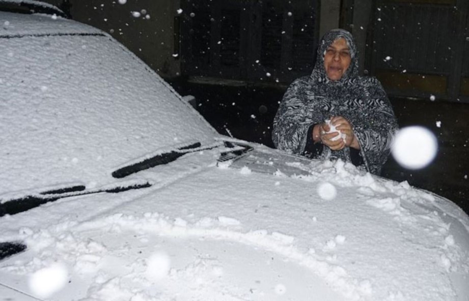 SEORANG wanita mengabadikan kenangan ketika salji turun di Baghdad. FOTO AFP