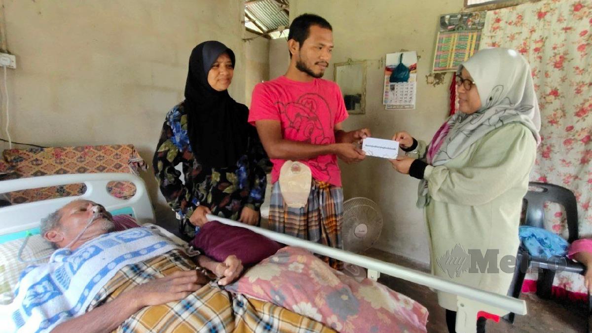 TUAN Zaimah (kanan) menyampaikan sumbangan kewangan serta barangan keperluan asas kepada keluarga Mohamad Fadzil. FOTO SYAHERAH MUSTAFA