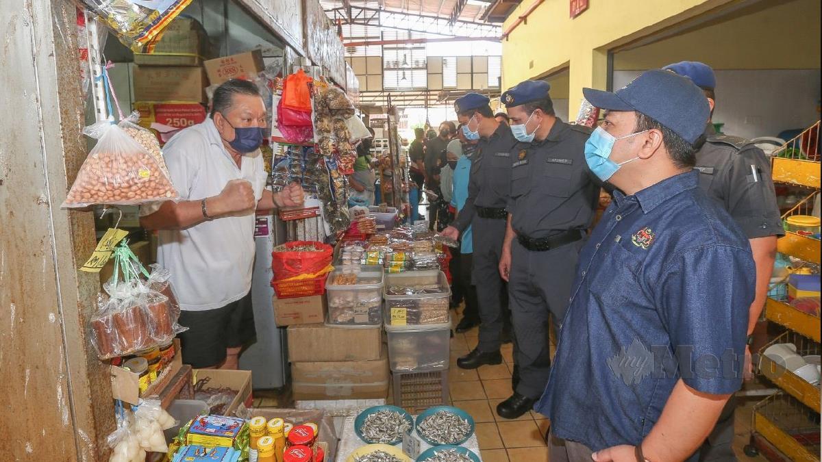 MUHAMMAD Zikril Azan Abdullah mendengar keluhan peniaga barangan runcit, Chng Bon Hu ketika memeriksa bekalan dan harga barang makanan. FOTO Fariz Iswadi Ismail