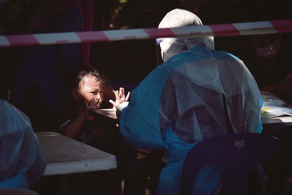 GELAGAT seorang kanak-kanak berhadapan petugas kesihatan yang membuat saringan kesihatan dan ujian calitan COVID-19. FOTO Bernama