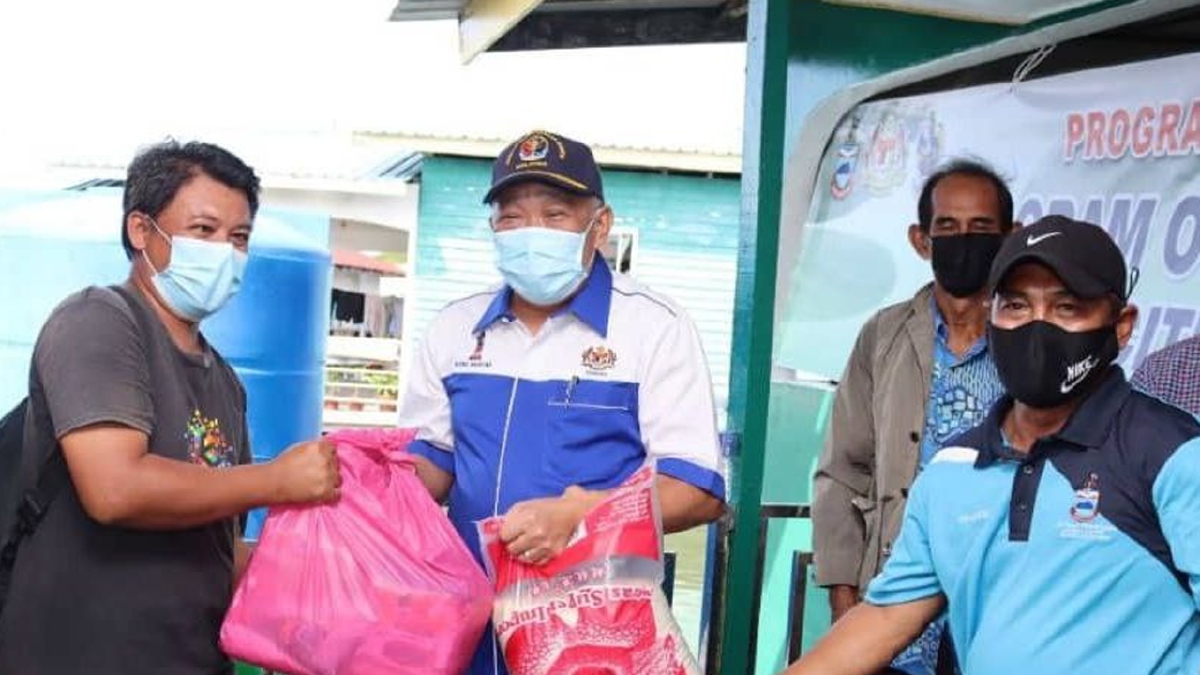 DATUK Seri Bung Moktar Radin (tengah) menyerahkan bakul makanan kepada penduduk di Kampung Sangau, Kinabatangan. FOTO ihsan pembaca