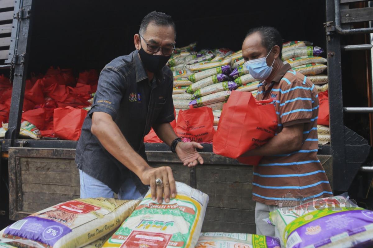 DATUK Rosol Wahid (kiri) menyampaikan bantuan bakul makanan kepada penduduk di Kampung Tajin, Kuala Berang. FOTO Ghazali Kori
