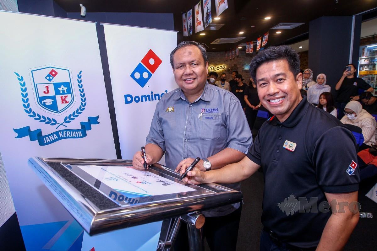 Shamsul Amree (kanan) bersama Ruzairi menandatangani plak sebagai tanda kerjasama Domino’s dan UTHM. - FOTO NSTP