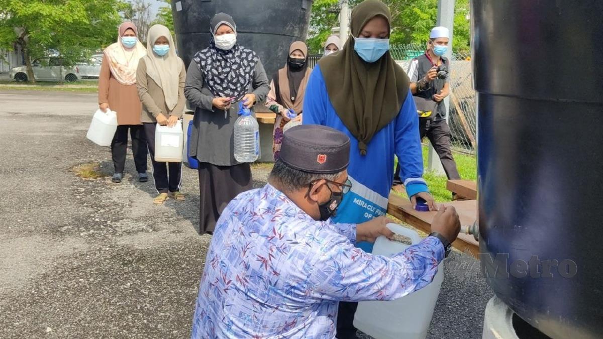 DATUK Dr Mohd Khairuddin Aman Razali membantu penduduk mendapatkan bekalan air bersih pada program Misi Bantuan Air di Dewan Serbaguna Tepuh. FOTO Zaid Salim