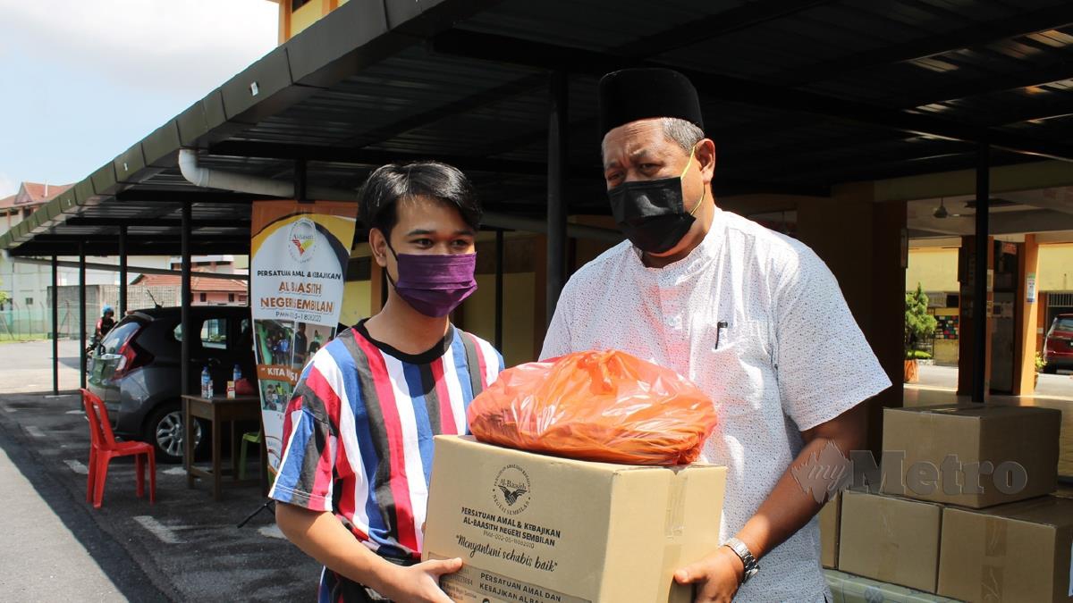ADLI Adnan menerima sumbangan barangan daripada Jafri Muskiman di SMK Mambau, hari ini. FOTO Mohd Amin Jalil