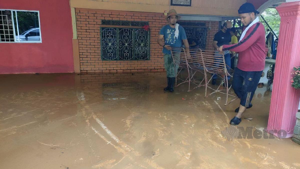 PENDUDUK di Kampung Seri Perigi membersihkan kawasan rumah mereka yang dipenuhi lumpur selepas banjir kilat akibat kepala air yang melanda semalam. FOTO Zuliaty Zulkiffli
