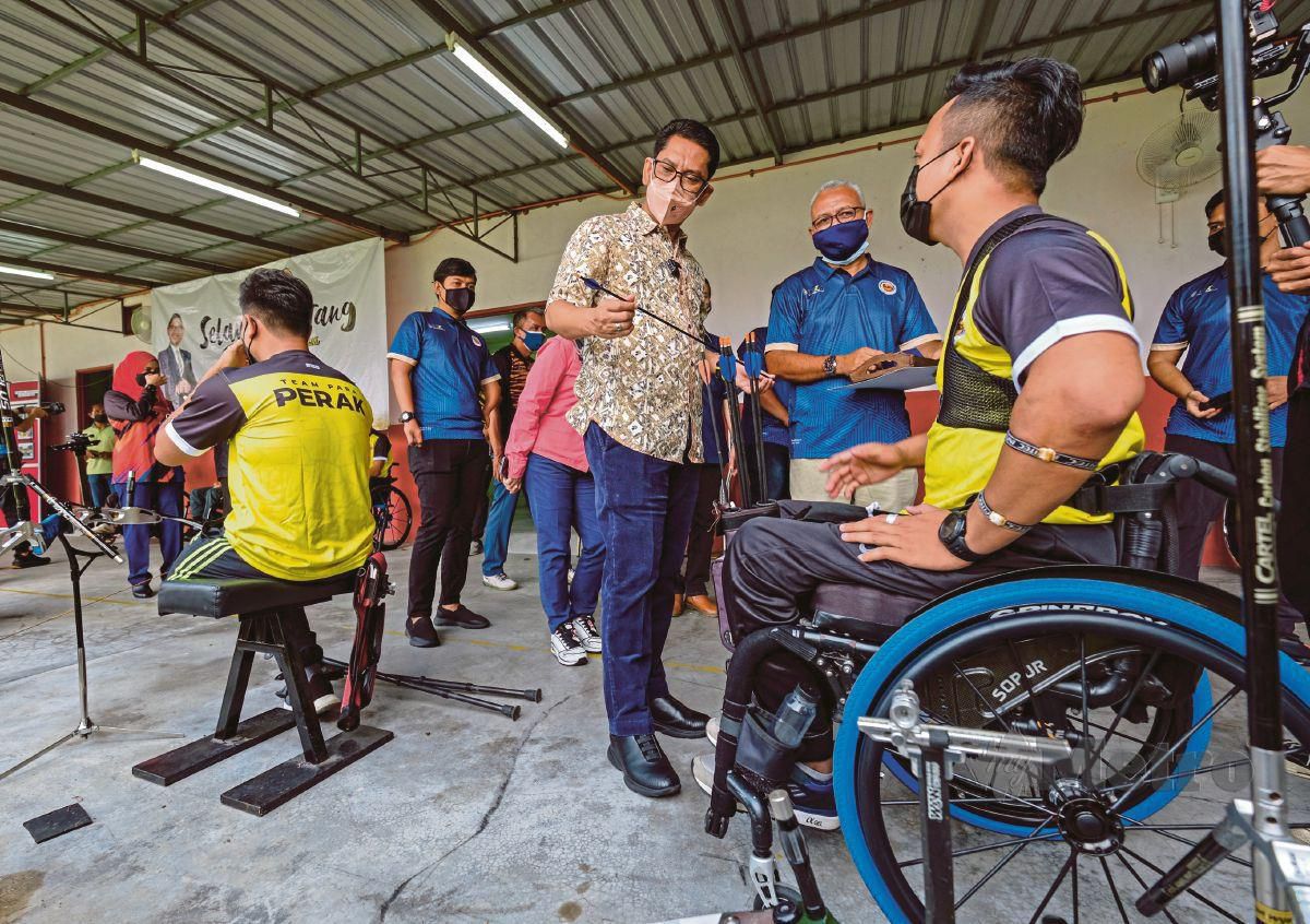 DATUK Seri Ahmad Faizal Azumu (tengah) melihat anak panah atlet memanah Paralimpik Perak, Mohamad Saiful Abdul Manan (kanan). FOTO Bernama