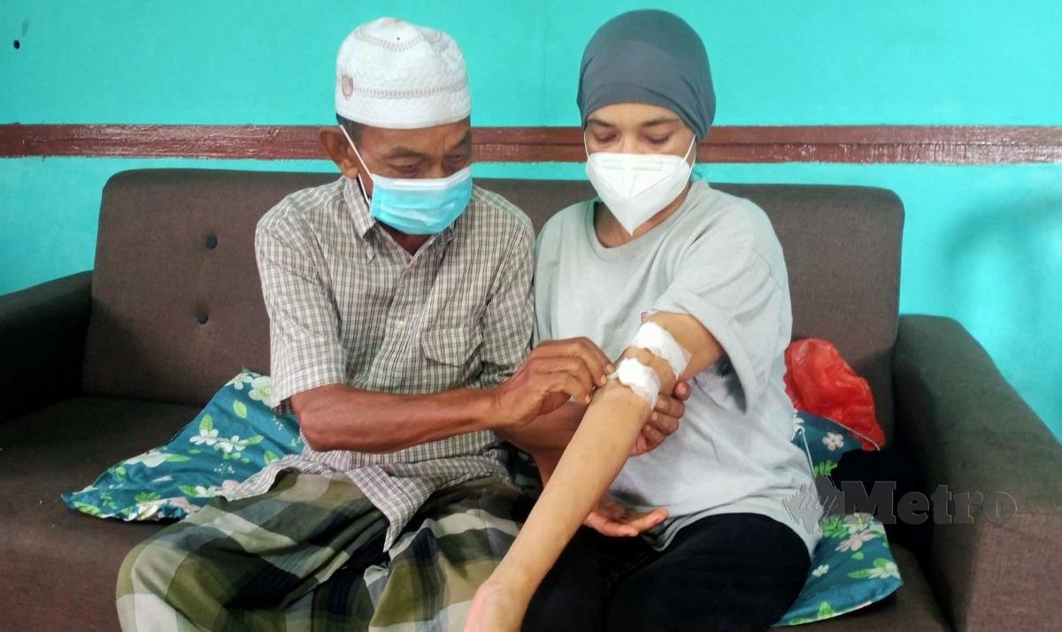 NAIMAT (kiri) melihat tangan isterinya, yang menghidap masalah buah pinggang rosak ketika ditemui di rumahnya di Port Dickson. FOTO Mohd Khidir Zakaria