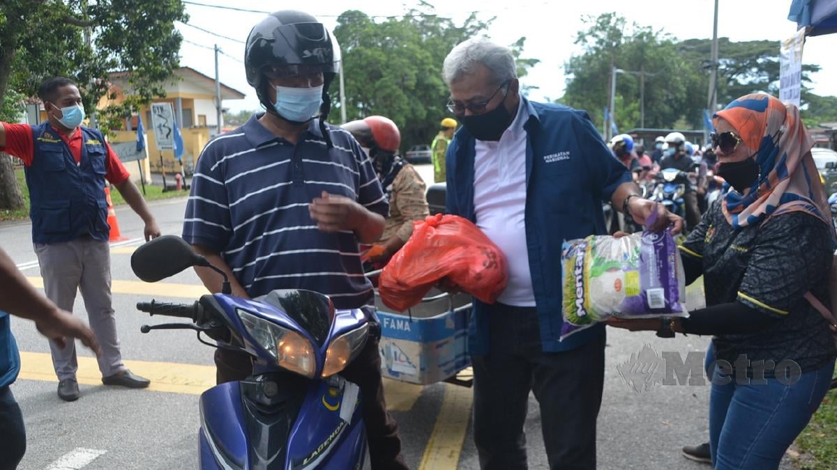 MOHD Redzuan Mohd Yusof menyerahkan sumbangan makanan kepada anggota komuniti di pekan Gadek, Alor Gajah hari ini. FOTO Hassan Omar