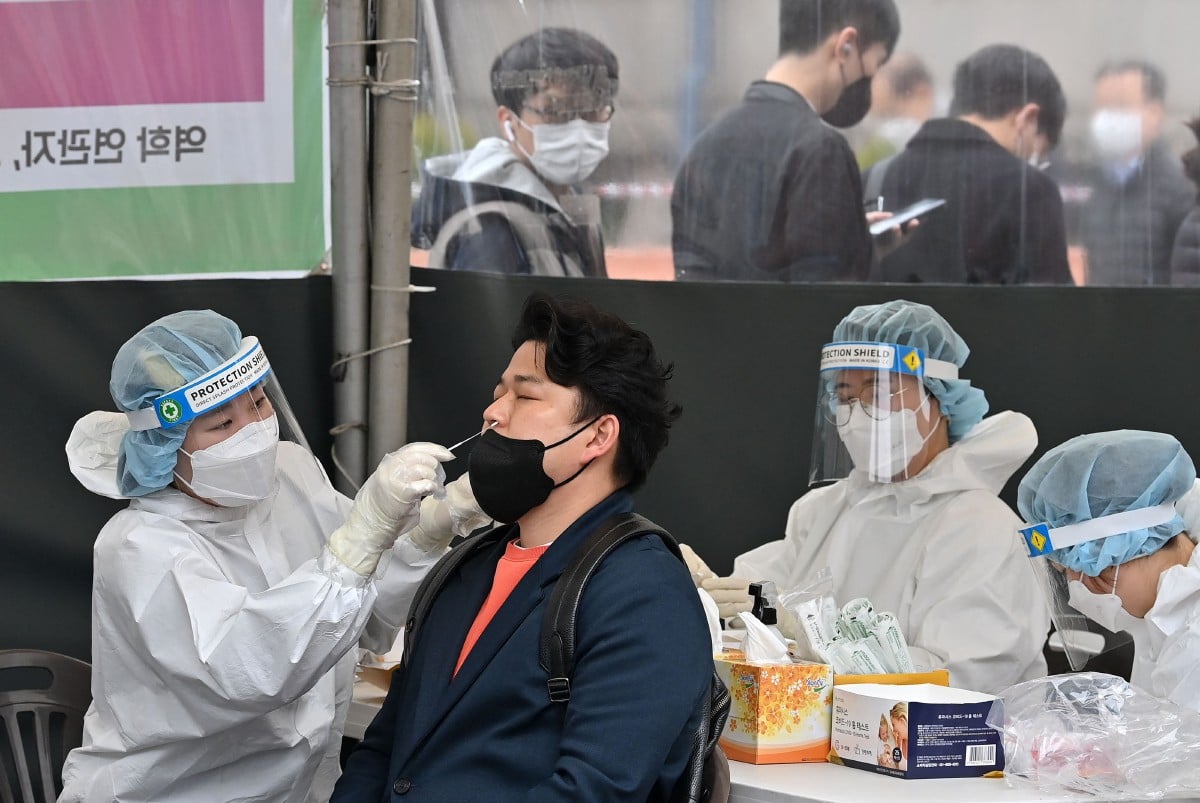 Kakitangan kesihatan mengambil sampel dari seorang lelaki bagi ujian pengesanan Covid-19 di Seoul. - FOTO AFP