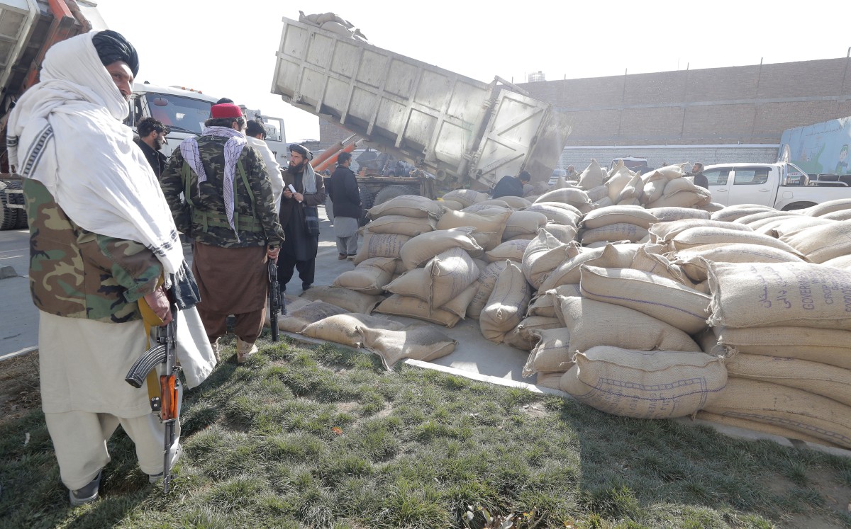 Anggota Taliban mengawal orang ramai yang beratur untuk mendapatkan gandum sebagai ganti gaji kerana tidak mempunyai aliran tunai mencukupi untuk membayar gaji kakitangan awam. - FOTO EPA
