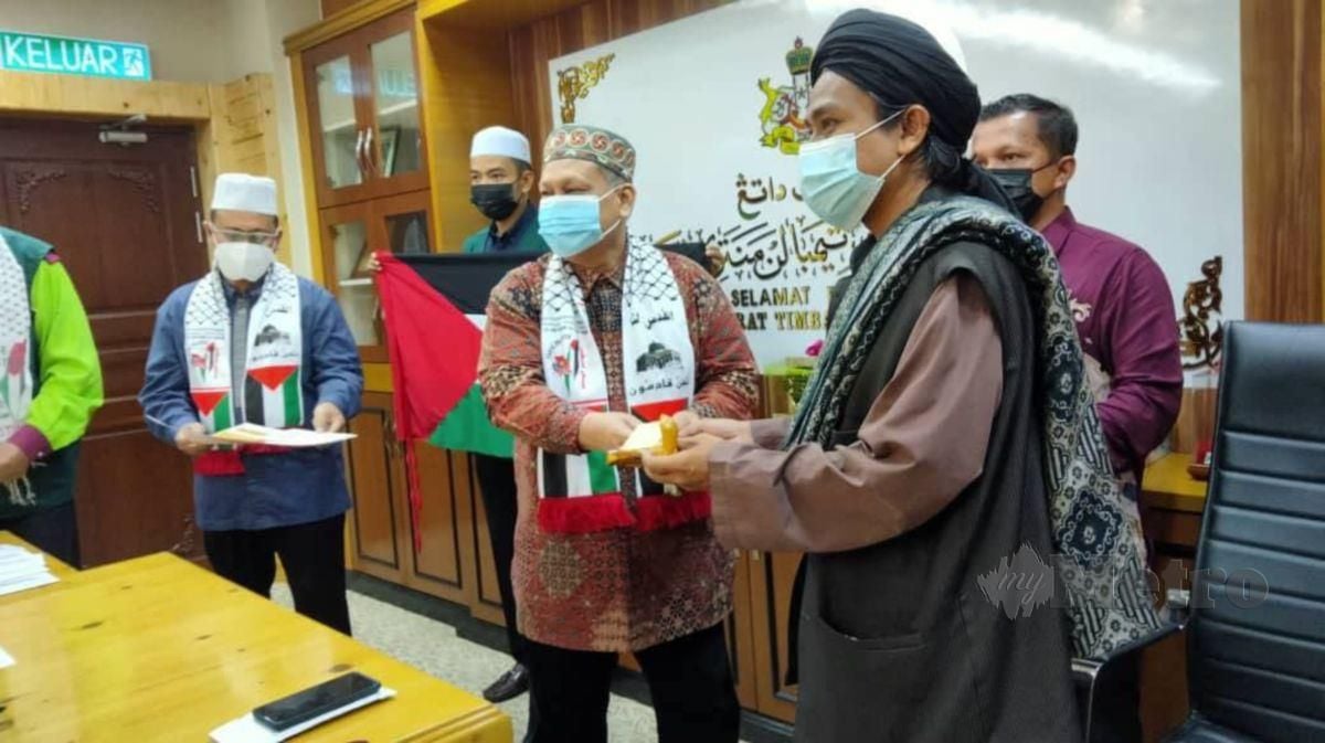DATUK Mohd Amar Nik Abdullah (tengah) menyerahkan keris miliknya yang dilelong kepada pembeli. FOTO Hazira Ahmad Zaidi
