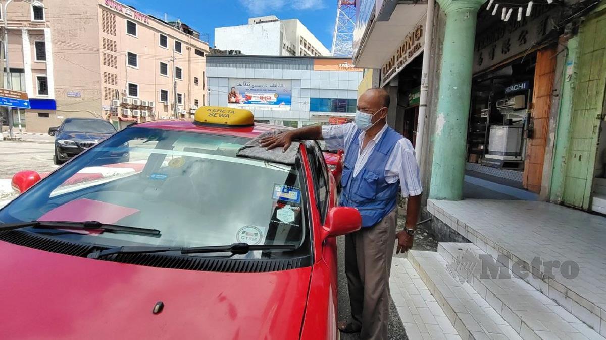 SHAFIIN Rahman mengelap kereta sewa miliknya sambil menunggu pelanggan, di sini, hari ini. FOTO Syaherah Mustafa