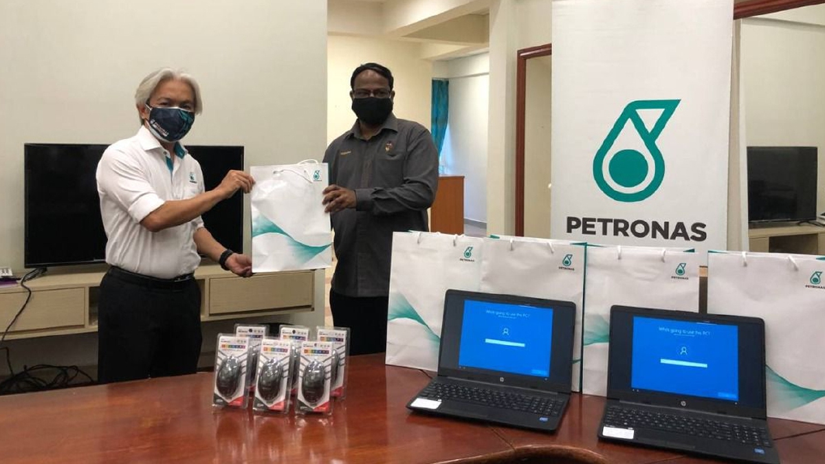 SAZLI Zakaria (kiri) menyampaikan sumbangan berupa komputer dan barangan kesihatan kepada S Veerapan. FOTO ihsan Petronas