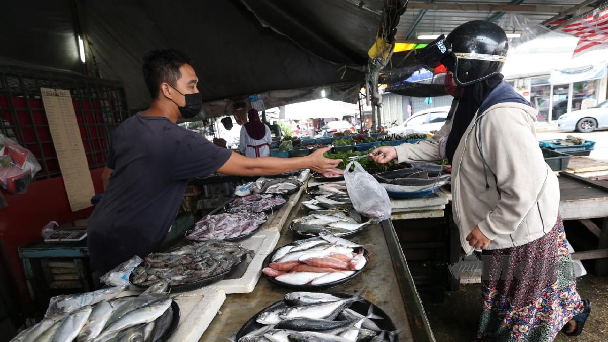 NIK Azli Nik Hassan, 44. melayan pelanggannya membeli keperluan barangan basah terutamanya bekalan ikan di Pasar Tok Guru Cabang Tiga, Pengkalan Chepa. FOTO Nik Abdullah Nik Omar