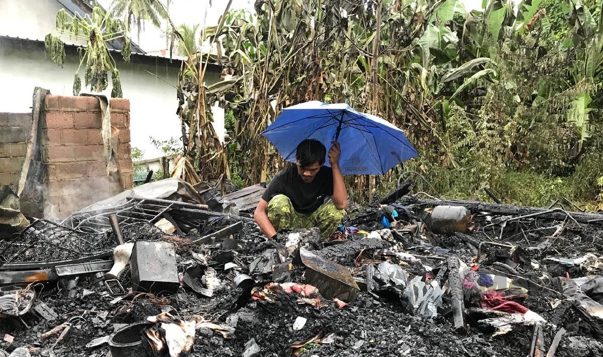MUHAMMAD Razlan Azhar melihat sisa kebakaran di tapak rumahnya yang terbakar di Kampung Pulau Belanga. FOTO Hazira Ahmad Zaidi