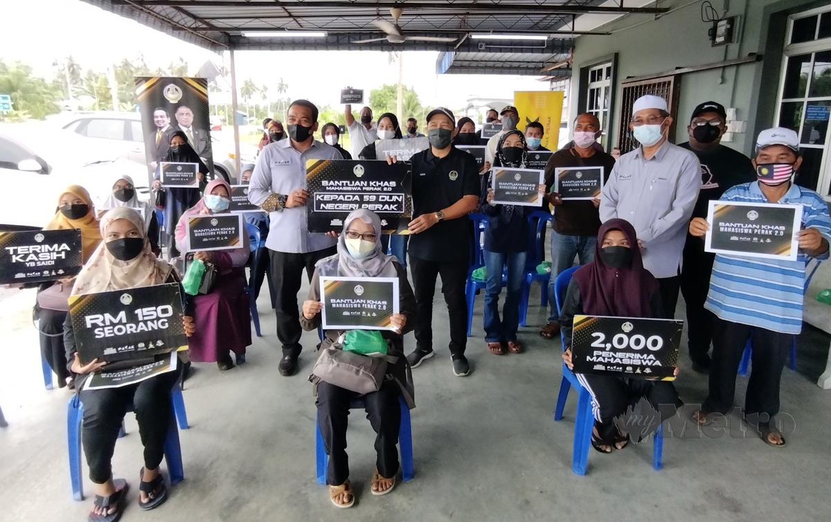 AHMAD Saidi (lima kiri berdiri) bersama 32 penerima bantuan mahasiswa DUN Kuala Kurau. FOTO Shaiful Sharin Ahmad Pauzi