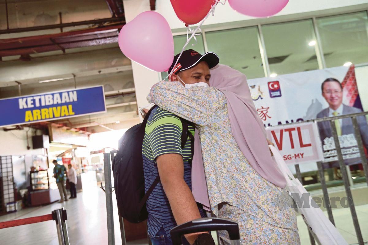 MUSHAIBAHFauzi, 32, memeluk suaminya Muhammad Wafi Akashah, 32, yang  tiba dari Singapura setelah lebih 10 bulan tidak pulang di Terminal Pengangkutan Awam Larkin Sentral, Johor Bahru. FOTO Nur Aisyah Mazalan