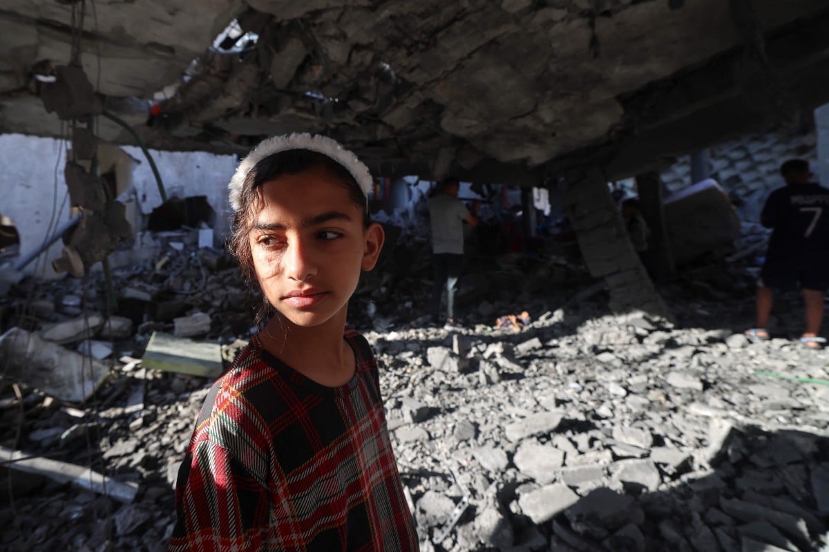 Kanak-kanak Palestin memeriksa bangunan yang musnah akibat pengeboman Israel di Rafah. FOTO AFP