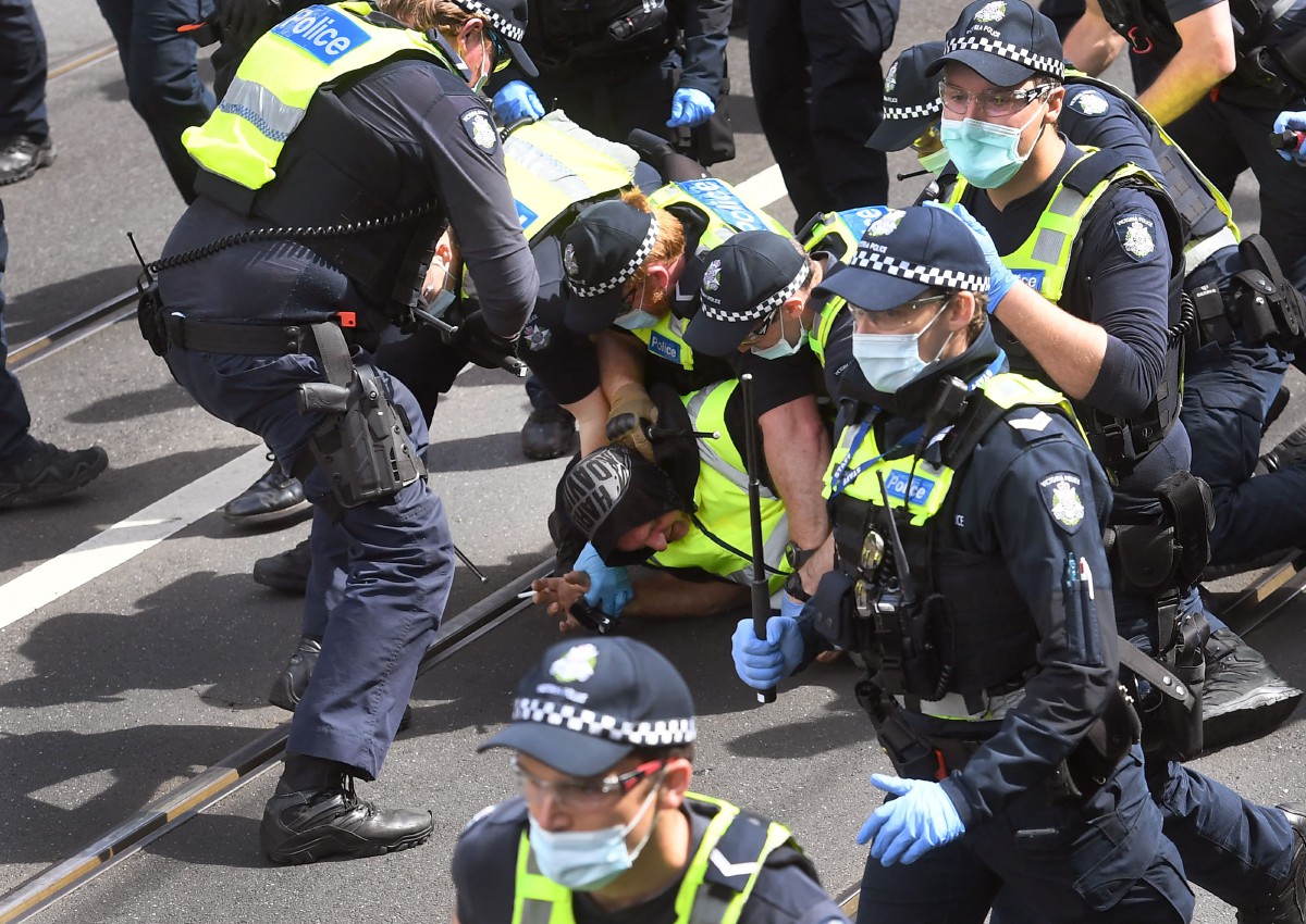 Polis menahan peserta protes di Melbourne. - FOTO AFP