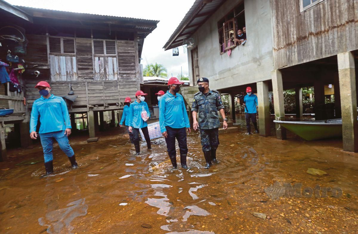 DATUK Ku Ardanan Dollah diiringi oleh  Superintendan Azhari Nusi meninjau sebahagian kawasan rumah penduduk kampung yang masih digenangi air banjir di Kampung Tersang, Rantau Panjang hari ini. FOTO Nik Abdullah Nik Omar