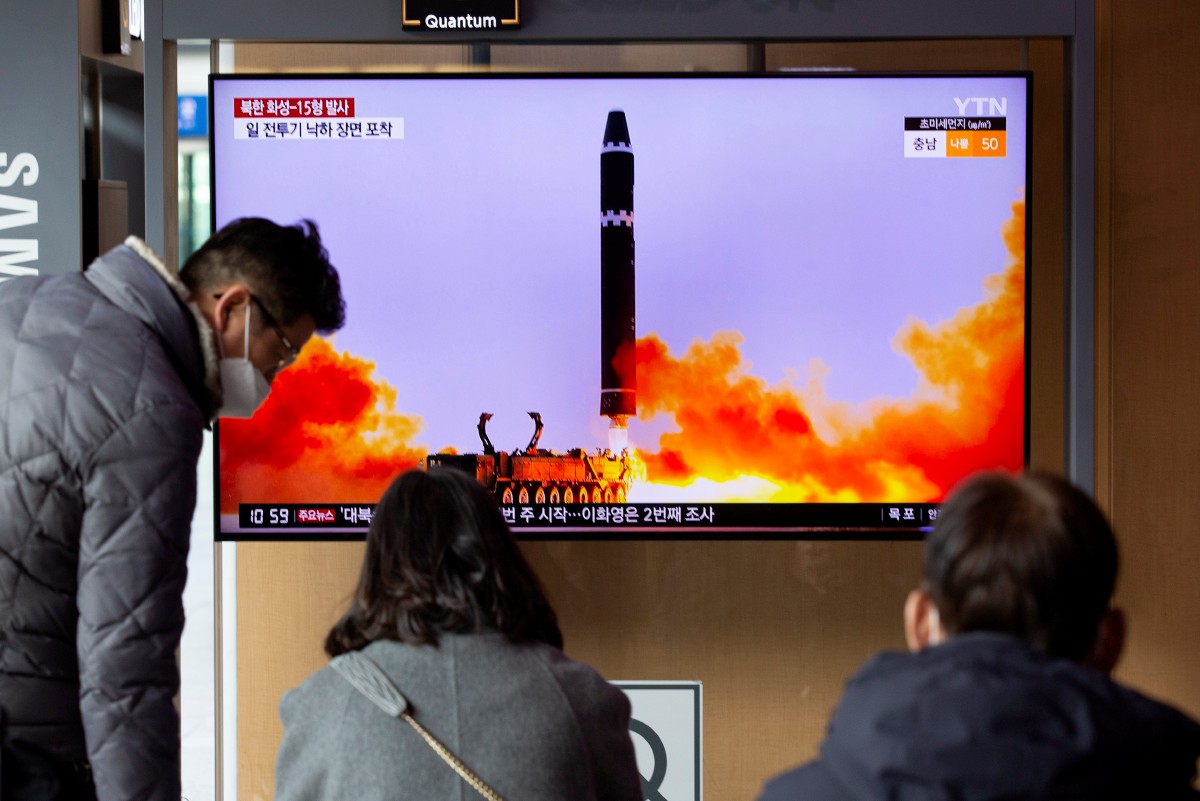 Orang ramai menonton berita mengenai pelancaran ICBM oleh Korea Utara. - FOTO EPA